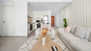 Un salon moderne avec un canapé, une table basse et une cuisine en arrière-plan.