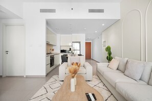 A modern living room with a sofa, coffee table, and a kitchen in the background.