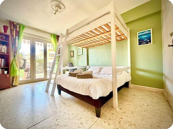 A bedroom with a bed, a ladder, a bookshelf, and a view through a sliding door. - At the gates of Cannes: Apartment 100m2 and terrace, center, Croisette on foot (Le Cannet)