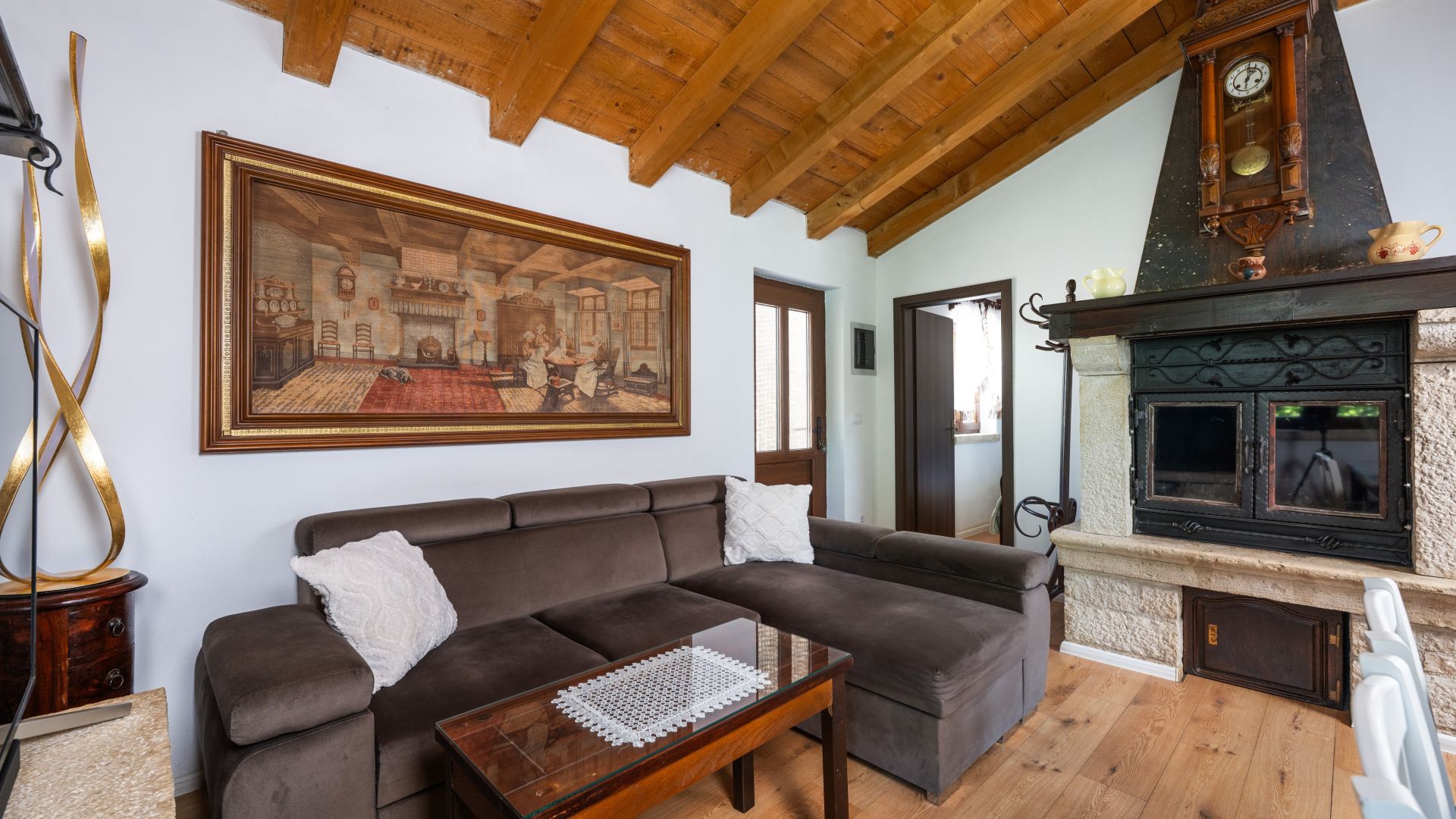Ein Wohnzimmer mit einem braunen Sofa, einem Glastisch, einem Kamin und einem großen, gerahmten Gemälde an der Wand.