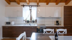 Une cuisine moderne avec des meubles blancs, un four à micro-ondes, une machine à café et une table à manger avec des chaises.