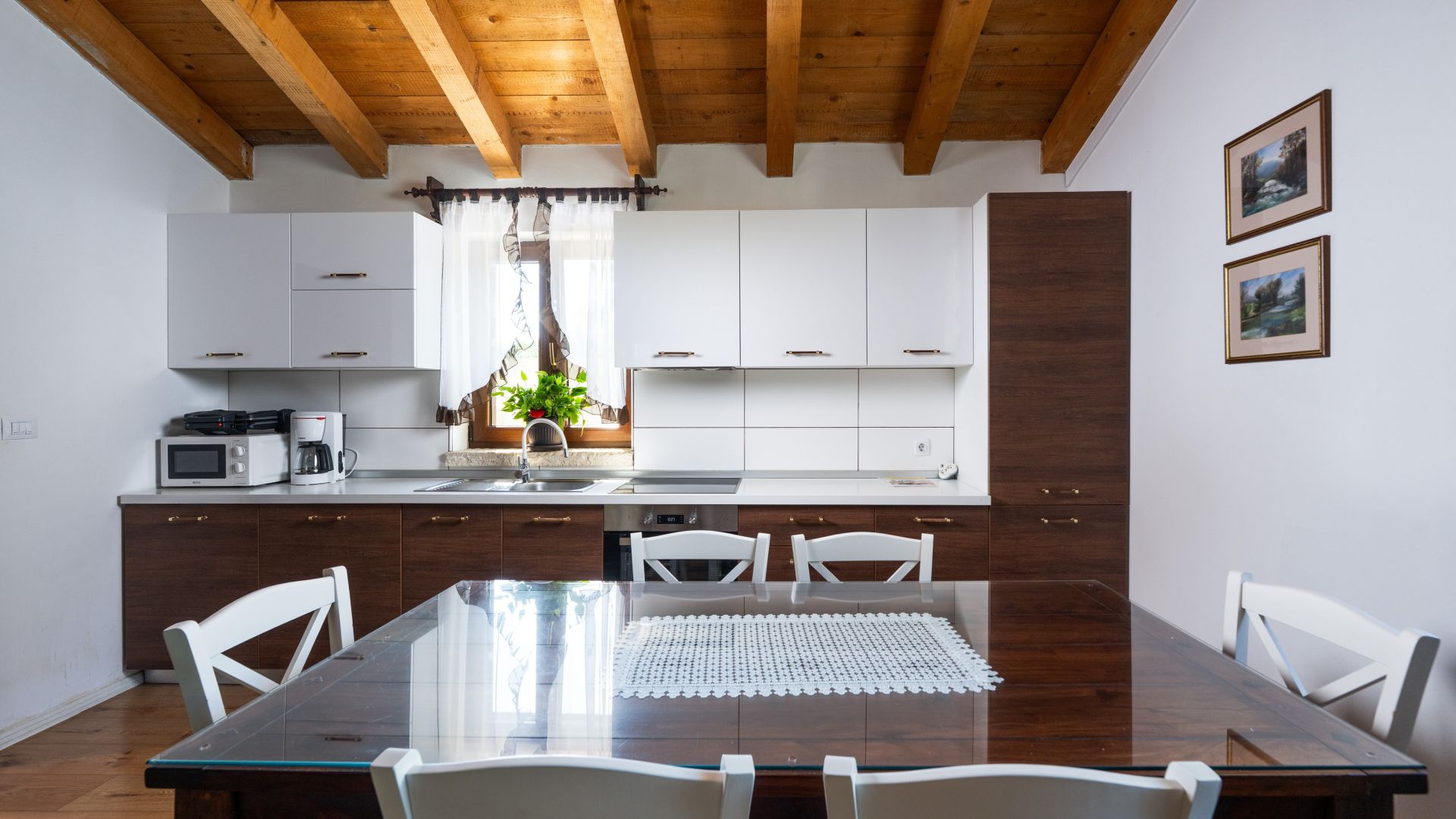 A modern kitchen with white cabinets, a wooden ceiling, and a dining table with chairs.