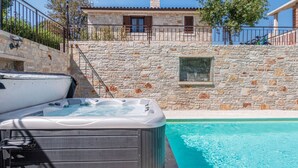 Un bâtiment en pierre doté d’une piscine, d’un jacuzzi et d’une rambarde en métal.
