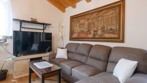 Un salon avec un canapé, un téléviseur, un tableau et une petite table.