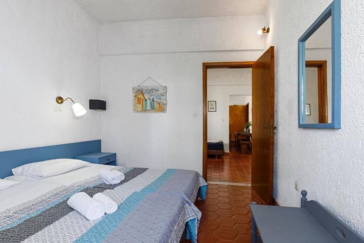 Una camera da letto con un letto, un comodino, una lampada a parete, un quadro incorniciato e uno specchio.