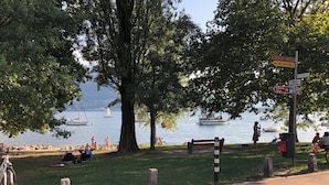 A lakeside park with a bench, a bicycle, and a signpost with directions.