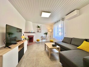 A modern living room with a fireplace, a sofa, a coffee table, and a TV. - Fully renovated air-conditioned house Hyper center Vieux Boucau Les Bains (Vieux-Boucau-les-Bains)