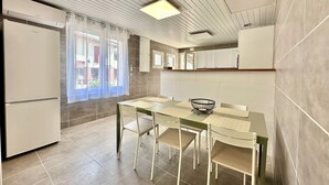 Una cocina moderna con comedor, muebles blancos y una ventana con cortinas.