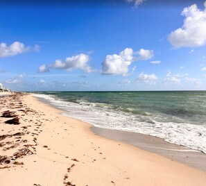 A beach with clear skies, waves, and footprints in the sand. - Oceanfront two-bedroom (Surfside)