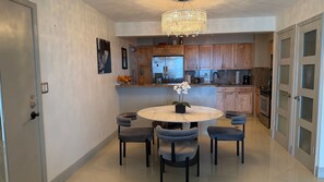 A modern kitchen with wooden cabinets, a stainless steel refrigerator, and a chandelier. - Oceanfront two-bedroom (Surfside)