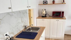 A kitchen with white cabinets, a wooden countertop, a coffee machine, a microwave, and a power strip. - Donna Flora's House (Napoli)
