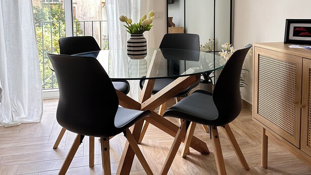 A modern dining area with a glass table, black chairs, and a wooden cabinet. - Donna Flora's House (Napoli)