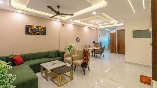 A modern living room with a green sofa, a coffee table, and a ceiling fan. - Tucson 2BHK Forest view by Homeyhuts (Dehradun)