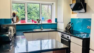 Uma cozinha moderna com ilha central, janela com vista para o verde e exaustor preto.