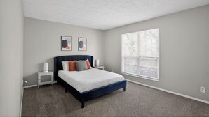A bedroom with a bed, nightstands, a window, and artwork on the wall. - Comfortable  2BR space near shops and dining (Riverdale)
