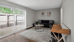 A modern living room with a sofa, coffee table, and a wooden side table. - Comfortable  2BR space near shops and dining (Riverdale)