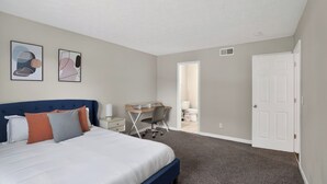 Ein Schlafzimmer mit einem Bett, Schreibtisch, Stuhl und zwei Wandbildern.
