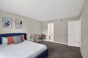 Ein Schlafzimmer mit einem Bett, Schreibtisch, Stuhl und zwei Wandbildern.