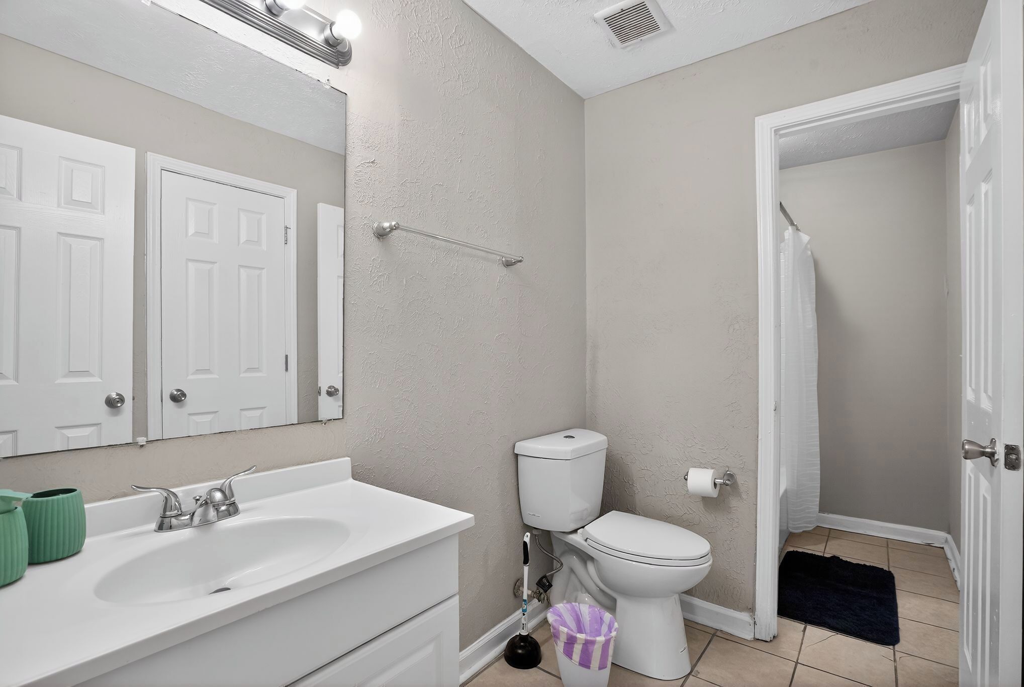 Une salle de bain avec un lavabo blanc, des toilettes et un rideau de douche.