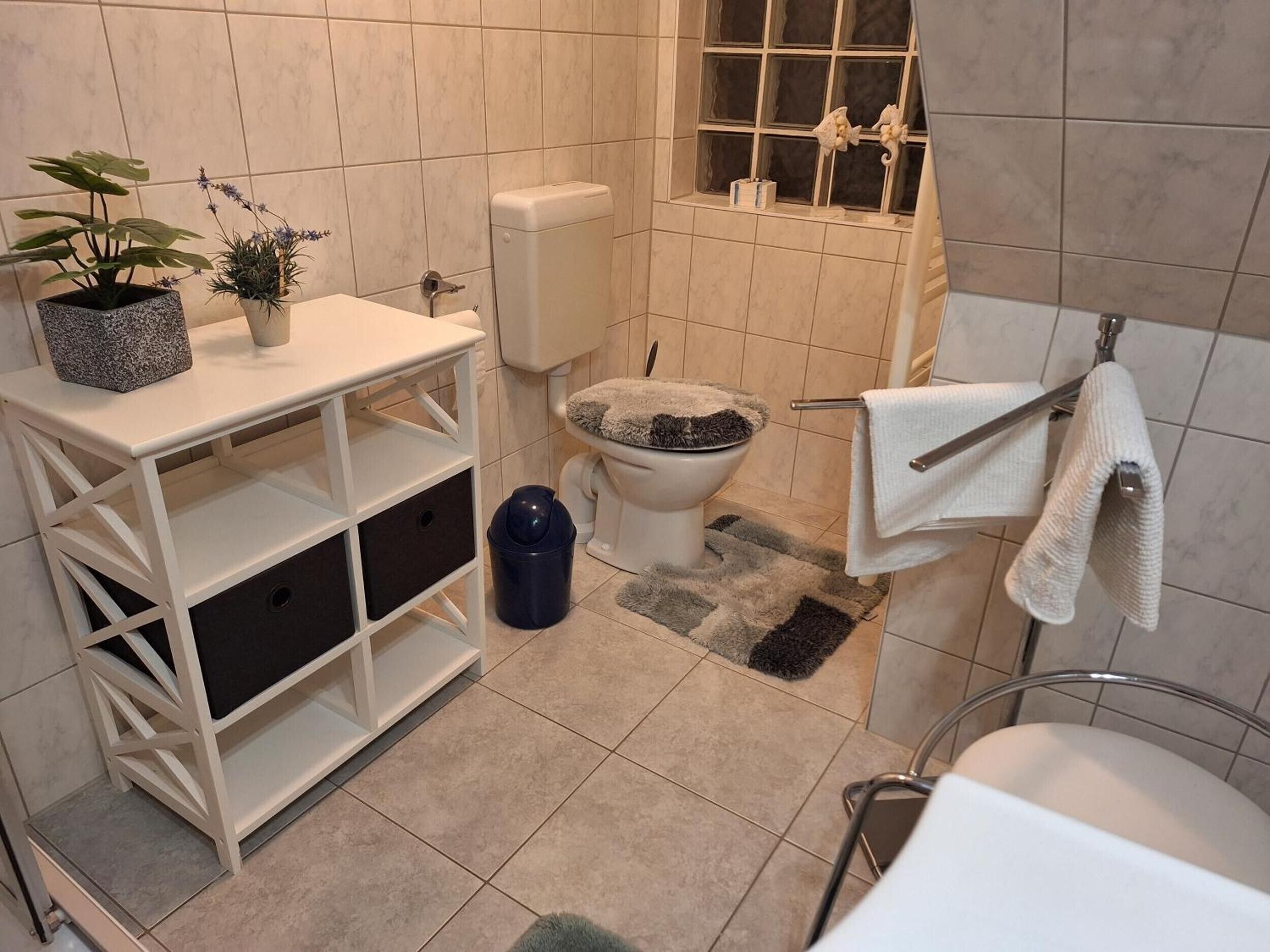 Un baño con inodoro, lavamanos y espacio de almacenamiento.
