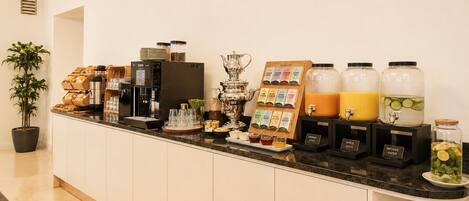 Una barra de desayuno con máquinas de café, una variedad de cápsulas de café y dispensadores de bebidas.