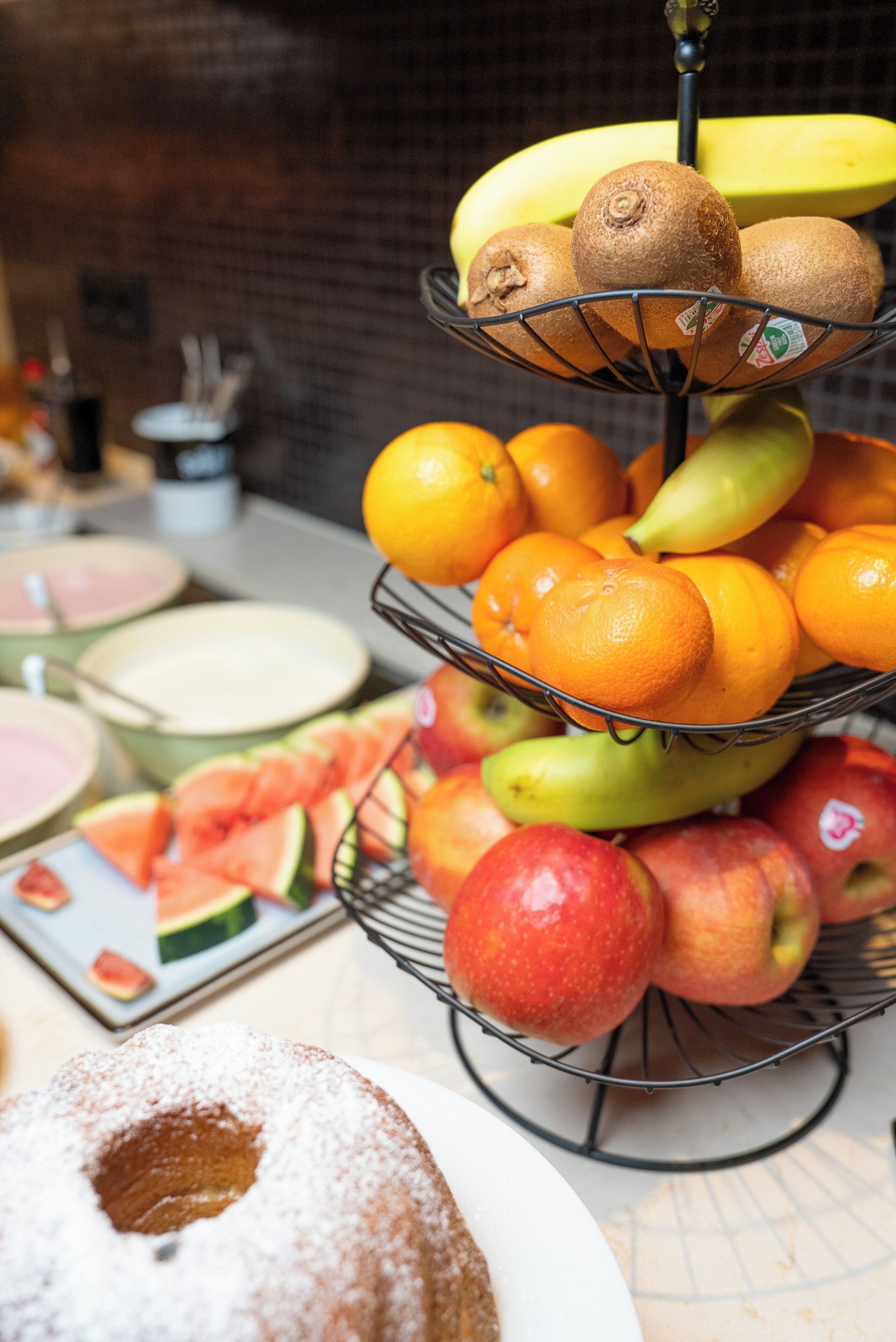 A fruit display with bananas, kiwis, oranges, pears, and apples.