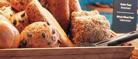 A wooden bread display with various types of bread, including seeded and whole wheat varieties.
