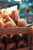 A wooden bread display with various types of bread, including seeded and whole wheat varieties.