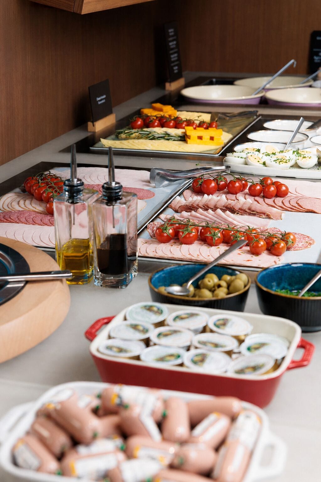 Una mesa de buffet con diversos alimentos, entre ellos, fiambres, quesos y verduras.