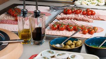Una mesa de buffet con diversos alimentos, entre ellos, fiambres, quesos y verduras.