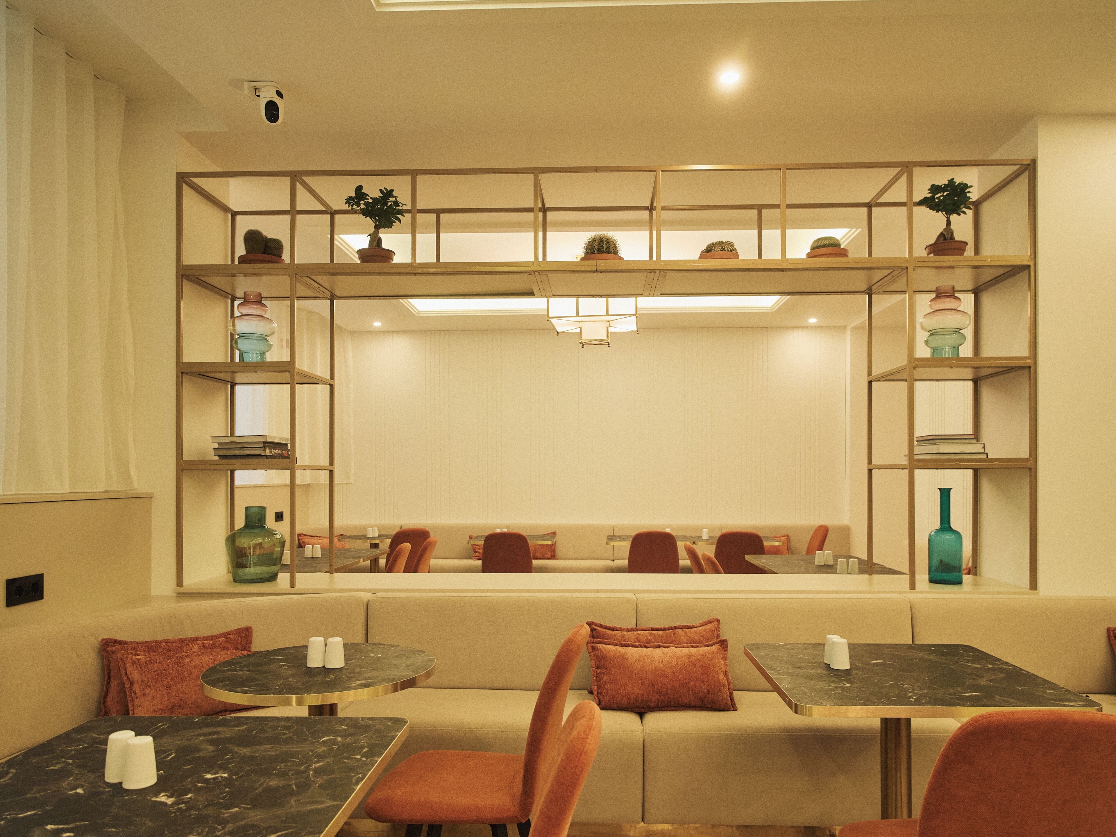 A hotel room with a dining area, a sofa, and a mirrored wall with shelves.