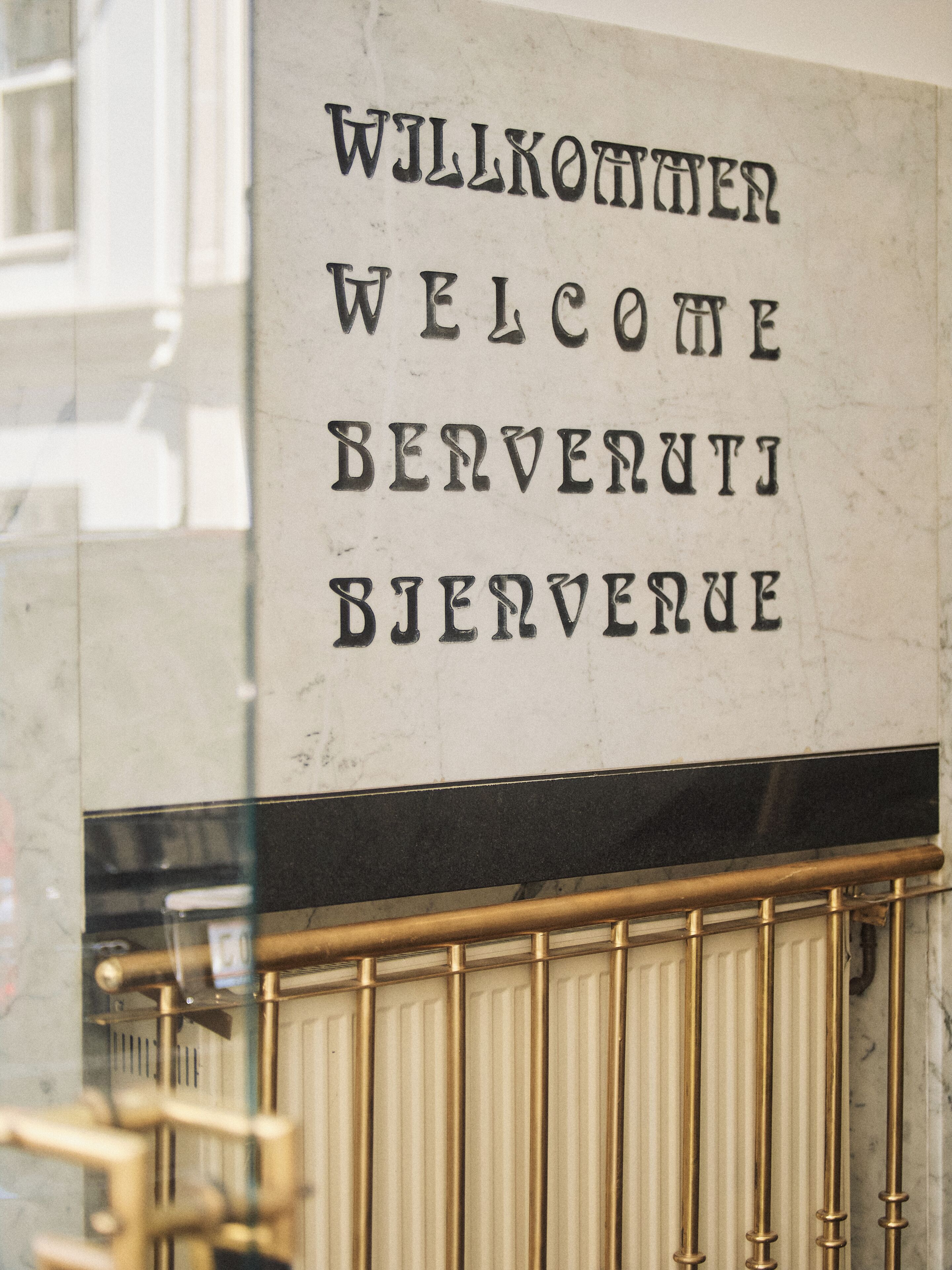 A sign with multilingual welcome text in English, German, and French.