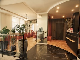 A modern hotel lobby with a staircase, seating area, and a reception desk.