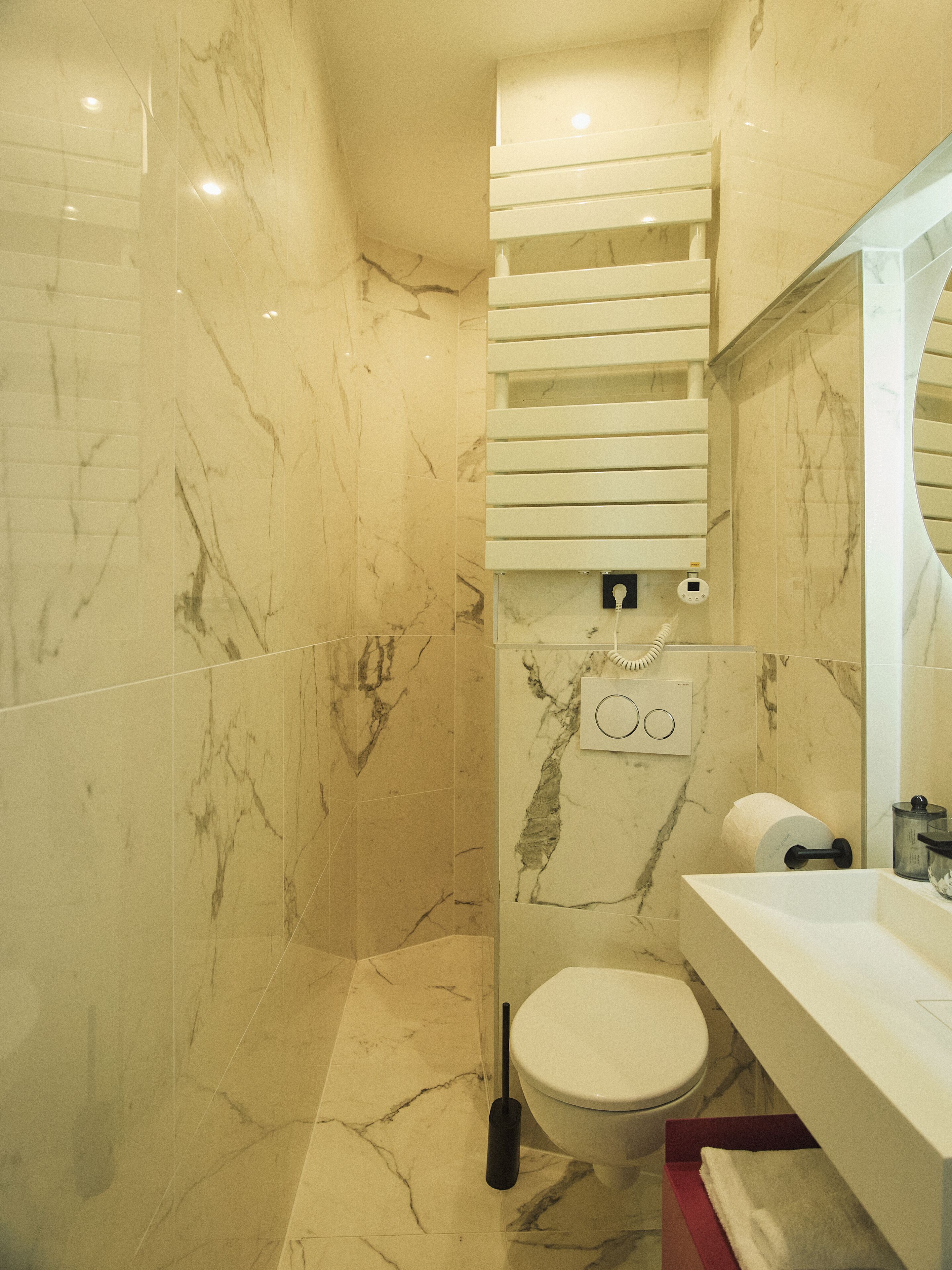 Ein Badezimmer mit Toilette, Waschbecken, Spiegel und Duschbereich.