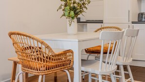 En matplats med flätade stolar, ett vitt bord och en vas med gröna växter.