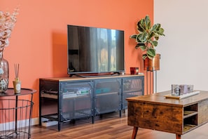 A modern living room with a large flat-screen TV, a wooden coffee table, a metal cabinet, and a potted plant. - Charming 2 Bedroom Apartment in Central London (London)