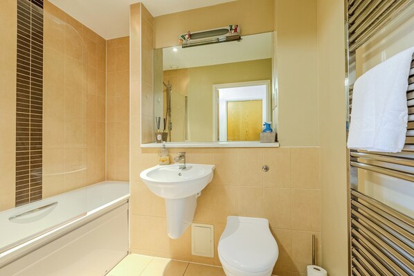 A bathroom with a bathtub, sink, toilet, and a mirror above the sink. - Charming 2 Bedroom Apartment in Central London (London)