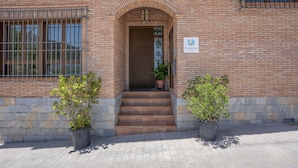 A brick building with a wooden door, steps leading to an entrance, and two potted plants on either side. - Apartment 'With Fireplace' with Mountain Views, Wi-Fi and Air Conditioning (Güejar Sierra)