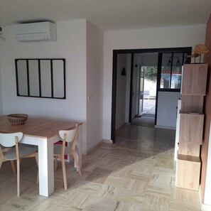 A dining area with a wooden table and chairs, a wall-mounted air conditioner, and a hallway leading to an outdoor area. - Upper Cassis with ocean views, 92m² air-conditioned apartment, swimming pool in the complex (Cassis)
