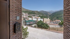 Un balcón con vistas a un pueblo, un buzón y el número 22.