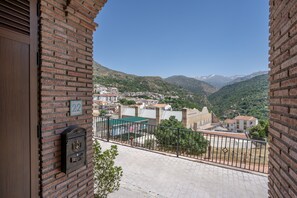 A balcony with a view of a town, a mailbox, and a building number 22. - Mulhacén Apartment with Mountain Views and Wi-Fi (Güejar Sierra)