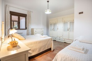 Un dormitorio con cama, mesita de noche, lámpara y armario.