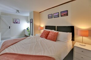 A neatly made bed with a headboard, bedside lamps, and a nightstand.