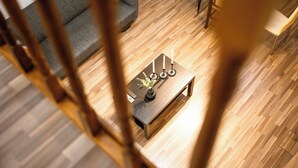 A modern living room with a wooden floor, a sofa, a coffee table with candles, and a dining area. - Apartment Sleeps 4 With Pets Welcome (Timisoara)