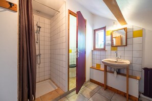 A bathroom with a shower, toilet, sink, and mirror.