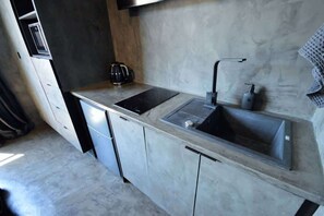 A modern kitchen with a built-in sink, a coffee maker, and a stainless steel countertop. - Trendy City Pad in Vibrant Location (Cape Town)