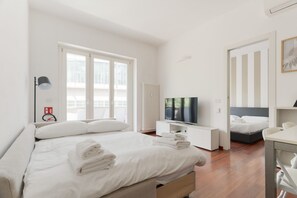 Et hotelværelse med en seng, et fjernsyn, et skrivebord og en anden seng.