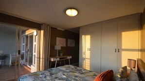 A bedroom with a bed, a desk, and a wardrobe. - Oceanfront Apartment w/Balcony, Table Mountain (Cape Town)