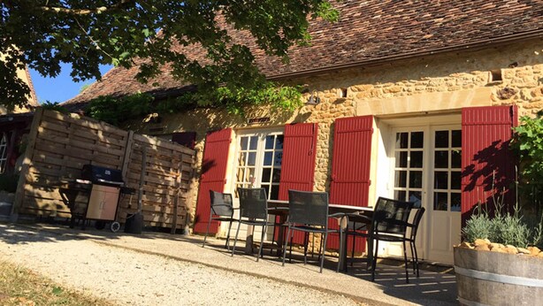 A stone building with red shutters, outdoor seating, and a gravel driveway. - PASTOUREAU (Sainte-Foy-de-Longas)