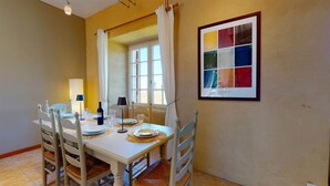 A dining area with a table set for four, chairs, a window with curtains, and a framed picture on the wall. - PASTOUREAU (Sainte-Foy-de-Longas)